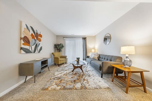 A living room with a grey couch, a wooden coffee table, and a painting on the wall.