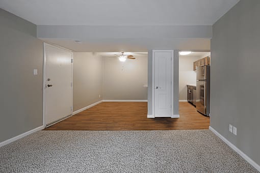 A room with a white door and a grey carpet.