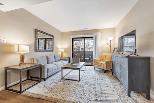 A living room with a grey couch, a yellow chair, a coffee table, and a television.