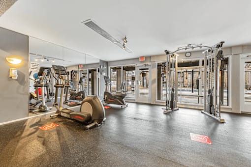 A gym with a variety of equipment including treadmills, stationary bikes, and weight machines.