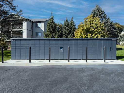 A large grey building with a blue door in the middle of a paved area.