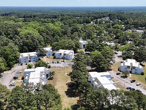 A bird's eye view of a white building surrounded by trees.