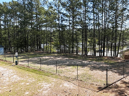 A fenced area with trees in the background.