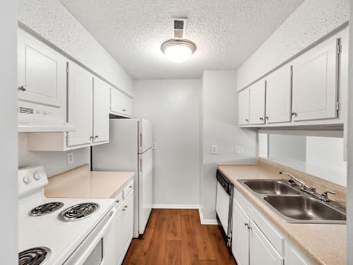 A white kitchen with wood floors and white appliances.