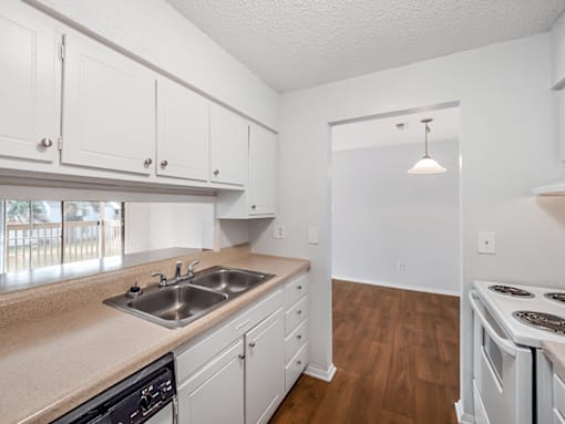 A kitchen with white cabinets and a wooden floor.