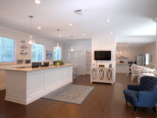 A spacious living room with a white reception desk and a blue armchair.