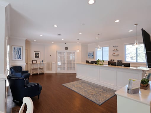 A spacious living room with a dark blue armchair and a white reception desk.