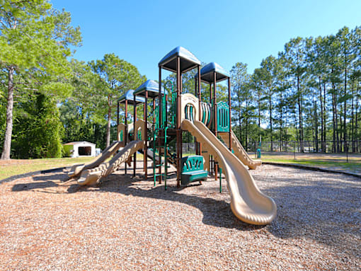 A playground with a yellow slide and a green roof.