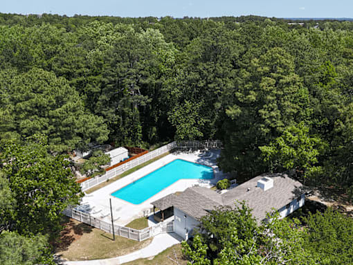 A house with a pool surrounded by trees.
