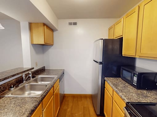 A kitchen with a black fridge and wooden cabinets.
