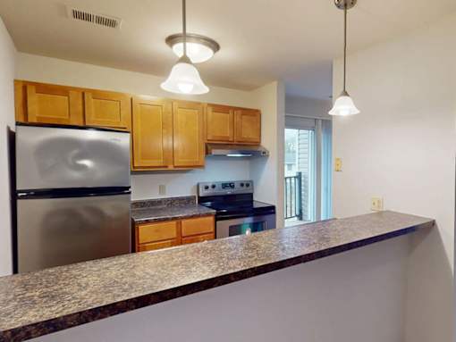 A kitchen with a granite countertop and wooden cabinets.