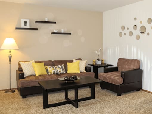 A living room with a brown couch, a black coffee table, and a brown armchair.