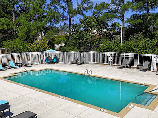 A small pool surrounded by a fence and trees.