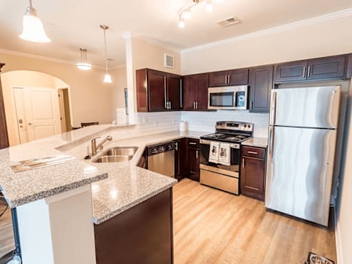 apartment kitchen with a granite counter top and stainless steel appliances