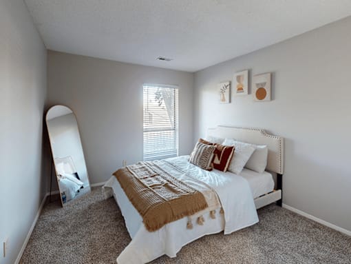 A bedroom with a bed, pillows, and a mirror.