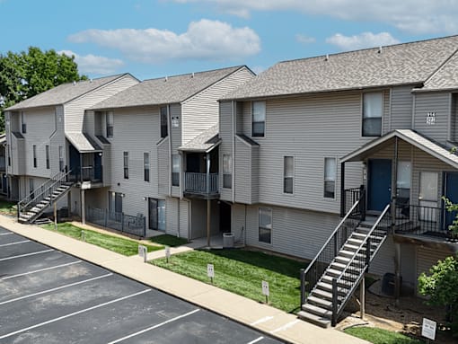 Apartment complex with a parking lot in front.