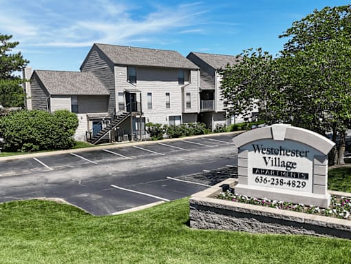 A sign for Westchester Village Apartments is in front of a building.