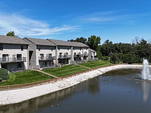 A row of houses with a pond in front of them.