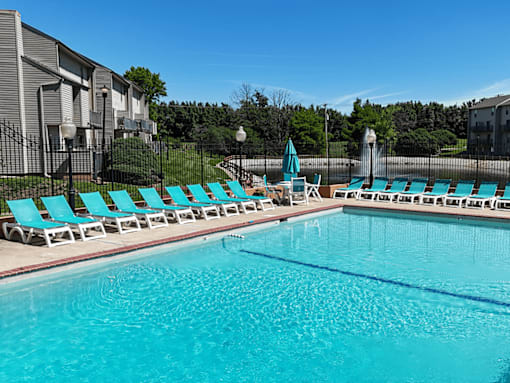 A swimming pool with blue water and lounge chairs.