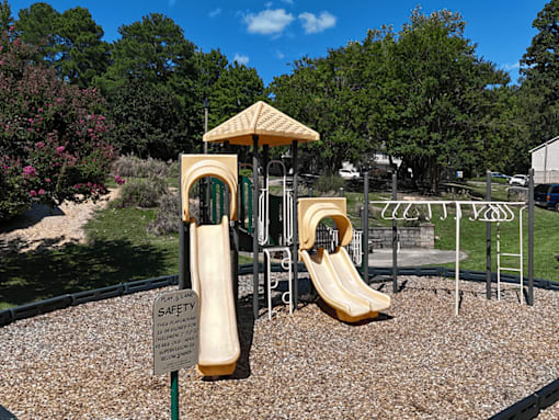 A playground with a yellow slide and a safety sign.