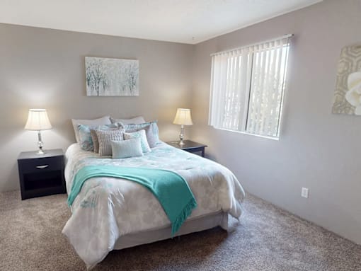 A bedroom with a bed, two lamps, and a painting on the wall.