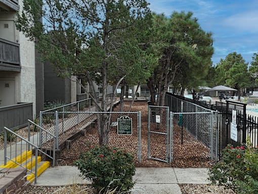 A sign in a fenced area with trees and bushes.