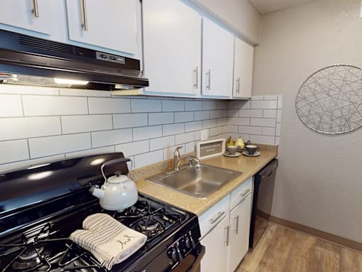 A modern kitchen with a black stove top and white cabinets.