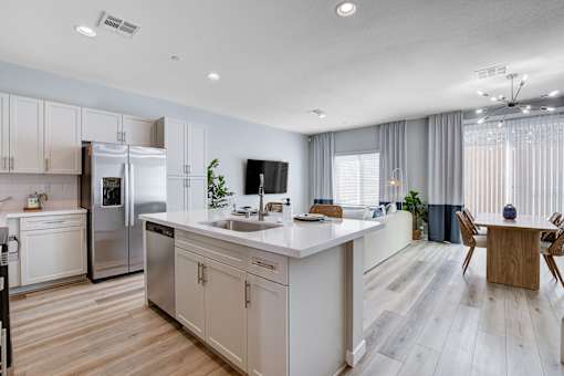 A modern kitchen with a refrigerator, sink, and dining table.at Copper Creek Apartments, Nevada, 89123