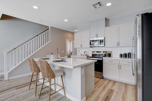 A kitchen with a white island and a refrigerator.at Copper Creek Apartments, Nevada