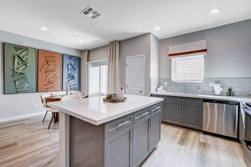 A modern kitchen with a white island and stainless steel appliances.at Copper Creek Apartments, Las Vegas