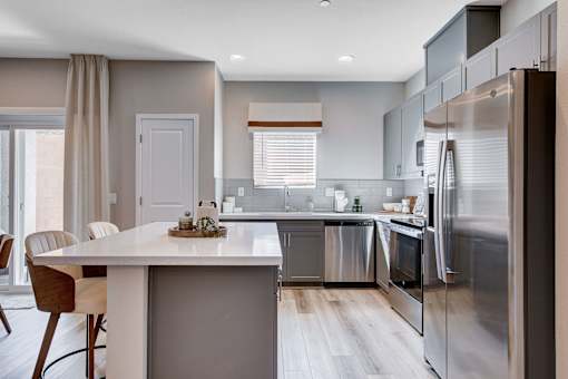 A modern kitchen with a dining table and chairs.at Copper Creek Apartments, Las Vegas, NV