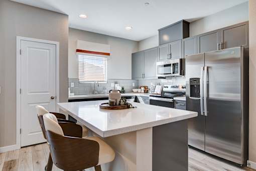 A modern kitchen with a white island and stainless steel appliances.at Copper Creek Apartments, Nevada