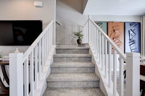 A staircase with a grey carpet and white railings.at Copper Creek Apartments, Las Vegas, NV 89123 