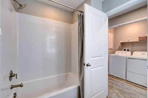 A white bathroom with a tub, toilet, and sink.at Copper Creek Apartments, Nevada