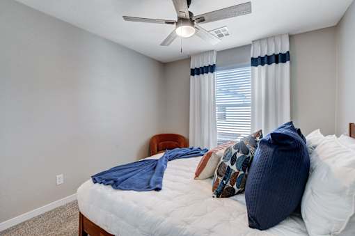 A bedroom with a bed, pillows, and a ceiling fan.at Copper Creek Apartments, Nevada, 89123