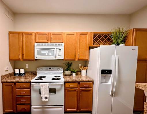 A kitchen with a white refrigerator and a white stove top oven.
