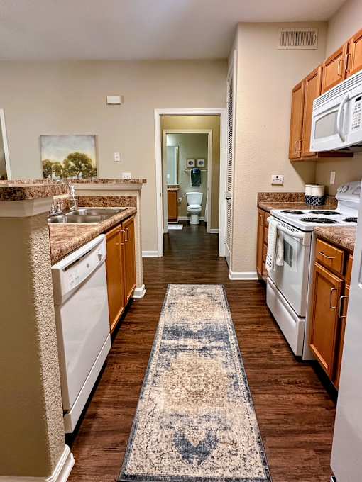 A kitchen with white appliances and wooden cabinets.