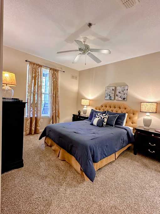 A bedroom with a bed, dresser, and ceiling fan.