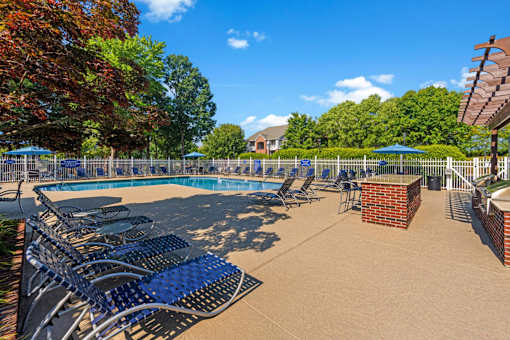 a swimming pool with blue lounge chairs and umbrellas