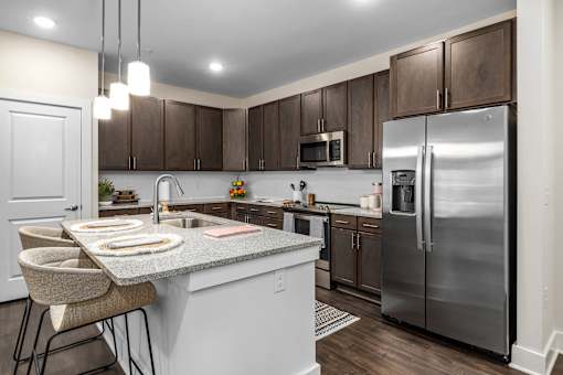 A modern kitchen with a granite countertop and stainless steel appliances.