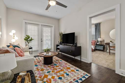 A living room with a white couch and a colorful rug.