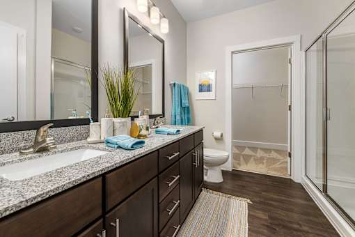 A bathroom with a sink, mirror, toilet, and a shower.
