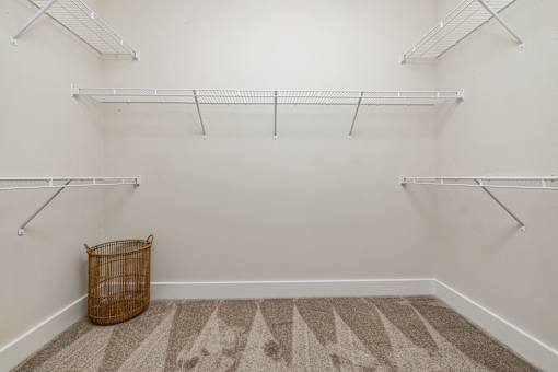 A room with white walls and a patterned carpet with a basket on the floor.