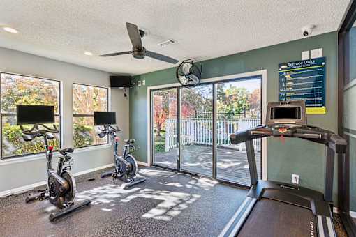 A gym with treadmills, exercise bikes and a fan.