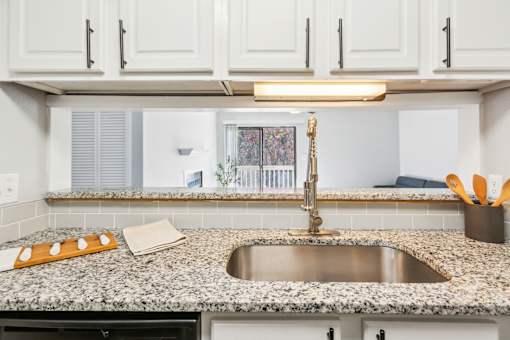 A kitchen with a granite countertop and a stainless steel sink.