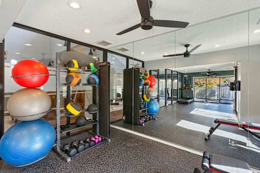 A gym with a variety of equipment including a rowing machine, a bench press, and a squat rack.