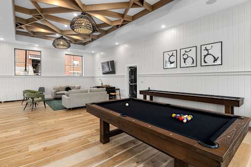 A pool table is in the middle of a room with a wooden floor and a wooden ceiling.