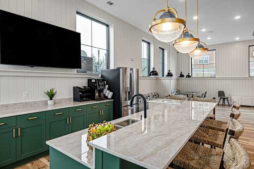 A modern kitchen with a marble countertop and green cabinets.