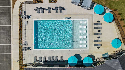 An aerial view of a swimming pool surrounded by lounge chairs and umbrellas.