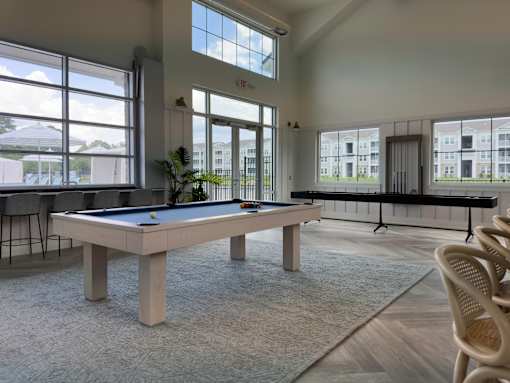 A billiard table in a room with a view of a building outside the window.